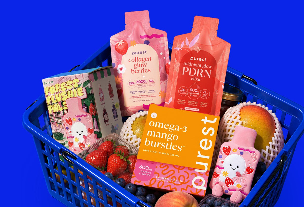 A Purest Mart shopping basket with Collagen Glow Berries, Midnight Glow PDRN Elixir, Omega-3 Mango Bursties, Purest Plushie Pals and fresh fruit