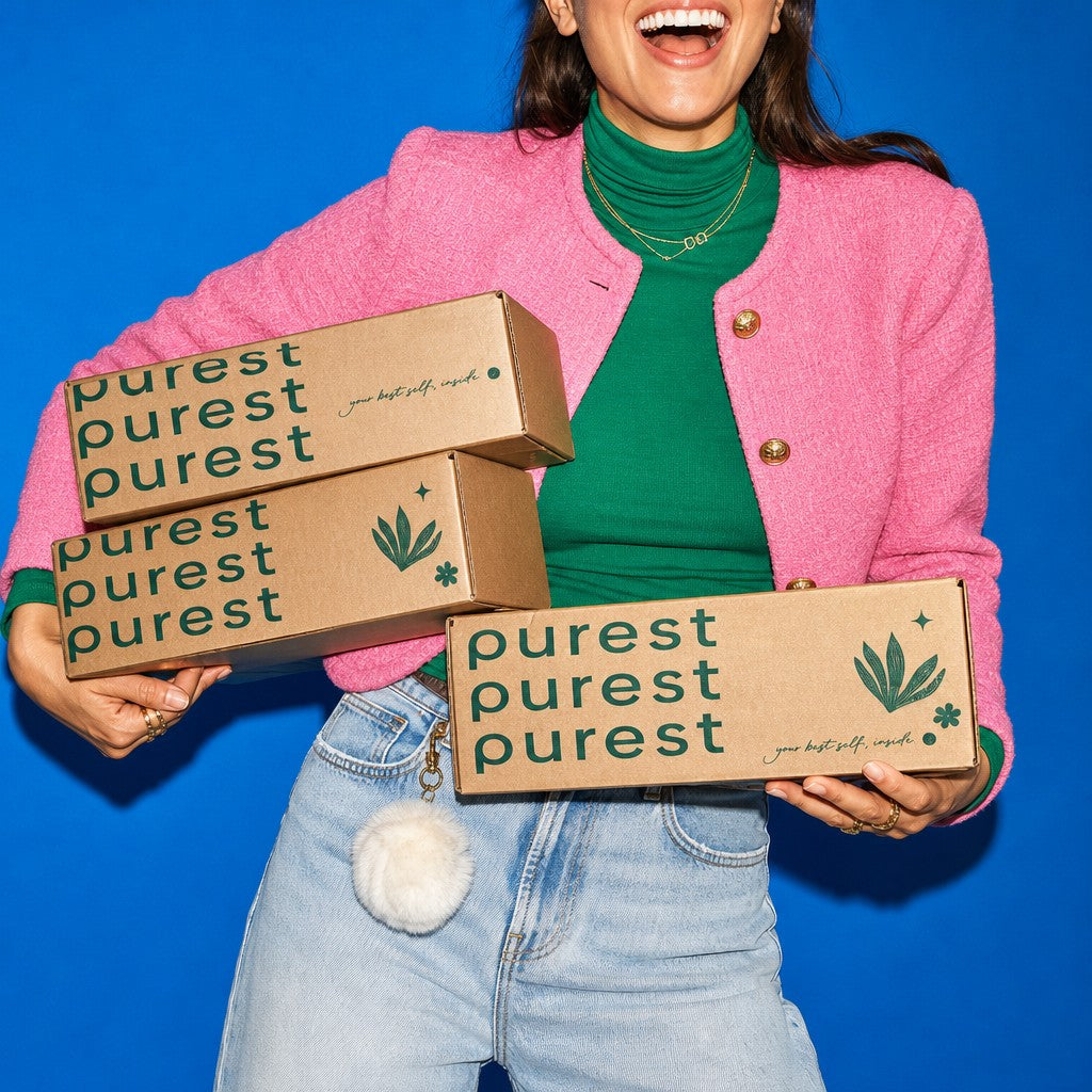 A smiling shopper carrying a stack of Purest delivery boxes
